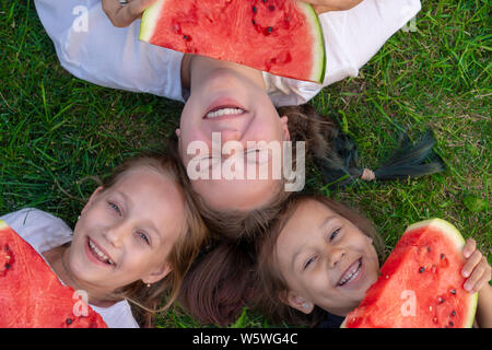 Drei Schwestern Sommer portrait. lächelnd Kinder outdoor. Kinder mit Wassermelone. Drei glücklich lächelnde Kind essen Wassermelone im Park. Konzept der Summe Stockfoto