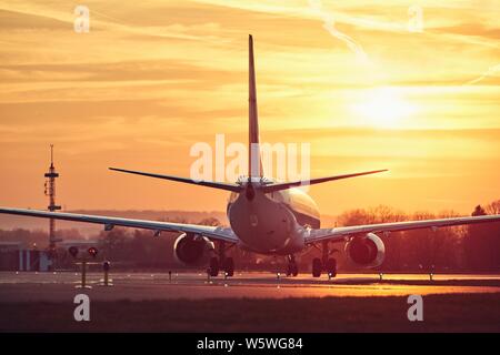 Das Flugzeug rollt zur Startbahn zum Abheben. Verkehr am Flughafen gegen Himmel während des Sonnenuntergangs. Stockfoto
