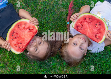 Zwei Schwestern Sommer portrait. lächelnd Kinder outdoor. Kinder mit Wassermelone. Zwei glücklich lächelnde Kind essen Wassermelone im Park. Konzept der Sommer Stockfoto