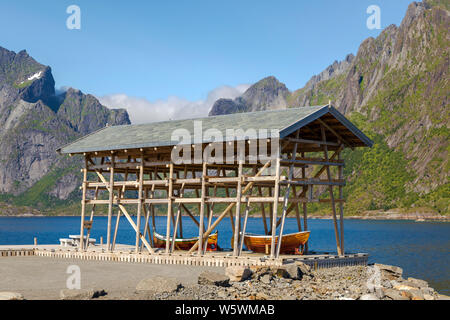 Trockenständer für Kabeljau mit Nordland Boote in Sakrisøy, ein Fischerdorf, Moskenes, Insel Moskenesøya, Lofoten Inseln, Norwegen, Stockfoto