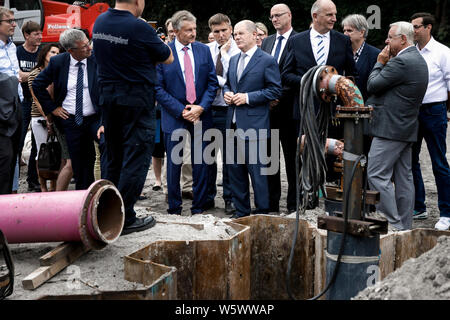 Oranienburg, Deutschland. 30. Juli, 2019. Karl-Heinz Schröter (links, m., SPD), Innenminister von Brandenburg, Olaf Scholz (rechts, m., SPD), Bundesfinanzminister und Dietmar Woidke (4. von rechts, SPD), Ministerpräsident des Landes Brandenburg, besuchen Sie die laufenden Dekonstruktion arbeiten an eine Bombe in einem schrebergarten Siedlung. Oranienburg wird zu einer Modellregion für Bombenentschärfung. Damit soll die Beseitigung von Blindgängern aus dem Zweiten Weltkrieg zu beschleunigen. Credit: Carsten Koall/dpa/Alamy leben Nachrichten Stockfoto