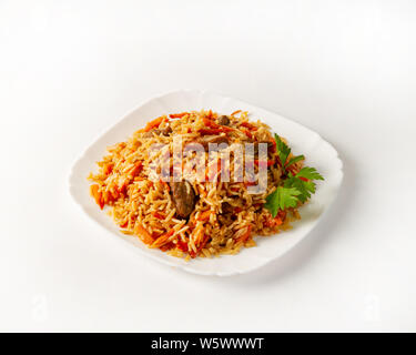 Teil von Rindfleisch Pilav, mit Petersilie auf einem weißen Hintergrund. Langkornreis. Traditionelle Küche in Zentralasien. Eintopf mit Karotten. Nahaufnahme Stockfoto