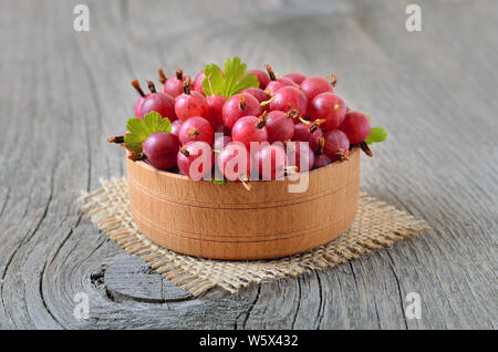 Rote Stachelbeeren in Schale auf Holztisch Stockfoto