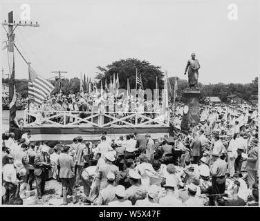 Präsident Harry S. Truman und andere Würdenträger auf der Überprüfung der Plattform, Bolivar, Missouri. Eine Masse ist um die Plattform versammelt, und eine Statue von Simon Bolivar steht zu Recht der Plattform. Präsident Truman spricht. Stockfoto