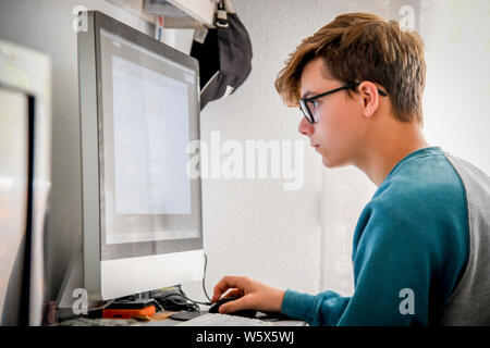 Schöne jugendlich Hausaufgaben mit dem Computer. Teenager online Arbeiten verbunden mit seinem Schulfreund. Technologie ermöglicht mit Fernbedienung frien zu kommunizieren Stockfoto