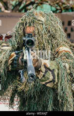 Getarnt Sniper hält Opfer mit Waffengewalt. Soldat gekleidet in Tarnanzügen durch Tarnung auf die Natur Stockfoto