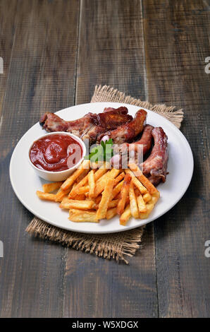 Pommes frites Kartoffeln, Rippchen und Tomatensauce auf weiße Platte Stockfoto