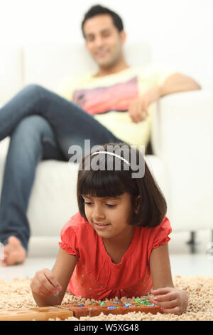 Indische Mädchen spielen Mancala-Spiel zu Hause Stockfoto