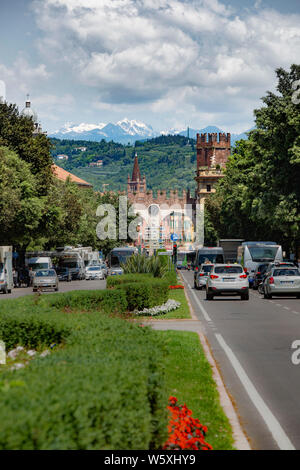 Verkehr auf Verona Via Nuova in Richtung Portini della Bra, aus dem 16. Jahrhundert Stadt Gateway. Wenig Dolomiten sind in der Ferne. Stockfoto