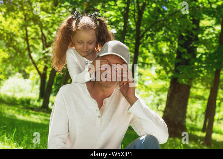 Happy Family! Das kleine Mädchen deckt ihre Väter Augen - sie macht eine Überraschung. Stockfoto