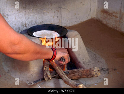 Eine ländliche indische Frau chapati Vorbereitung in traditioneller Weise auf einem Holzofen Stockfoto