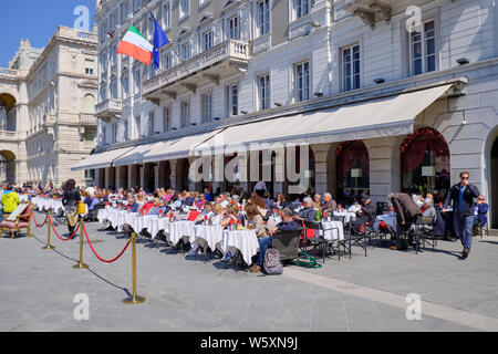 Menschen sitzen im Cafe an der Plaza Unita auf sonniger Frühlingstag in Triest, Italien, April 2019 Stockfoto