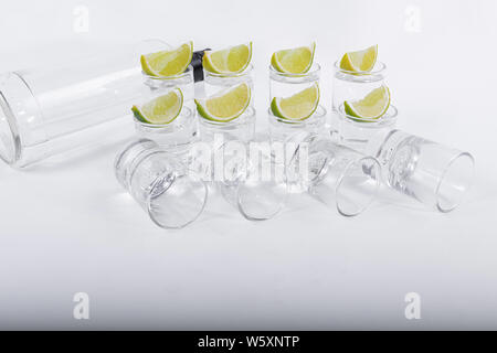 Luxuriöse Tequila in Gläser mit Zitronenscheiben oben serviert, zusammen mit einer Flasche tequila auf weißem Hintergrund isoliert - Close-up Stockfoto