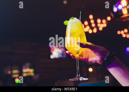 Cocktail Glas in der Frau hand mit Bar auf der Rückseite. Stockfoto