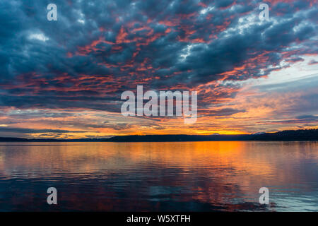 Die Wolken hängen am Himmel, wie die Sonne hinter den Olympic Mountains im Armaturenbrett, Washington. Stockfoto
