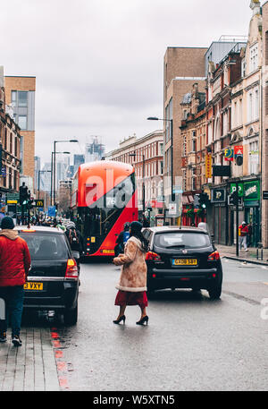 Eine stilvolle Frau durchquert die Straße in Dalston, East London im Winter. Stockfoto