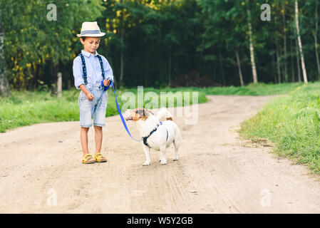 Kind Junge lernen, wie zahm und ein Hund an der Leine Zug Stockfoto