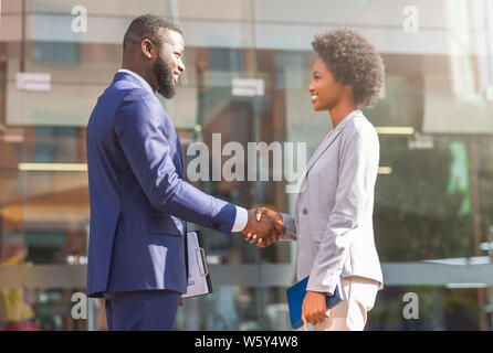 Junge afrikanische Geschäftsleute die Hände schütteln im Freien Stockfoto