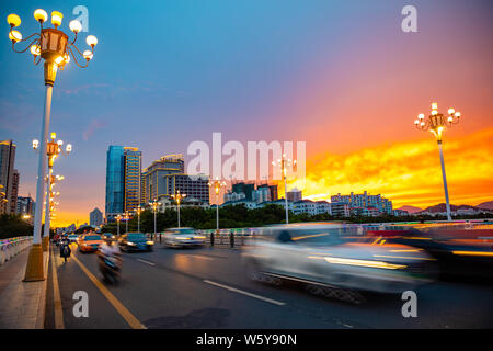 Sanya, Hainan, China - 26.06.2019: Sanya Stadtbild mit viel befahrenen Straße und Gebäude in den Sonnenuntergang, Hainan Provinz, China Stockfoto