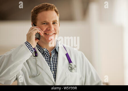 Porträt eines lächelnden männlicher Arzt sprechen auf einem Mobiltelefon. Stockfoto
