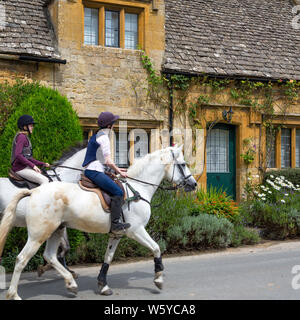 Reitpferde durch Cotswold Dorf Stanton, Gloucestershire, England Stockfoto