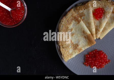 Blini Dreiecke oder Crepes mit rotem Kaviar auf Platte mit Jar Stockfoto