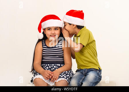 Junge flüstert zu seinen Schwesternohren Stockfoto