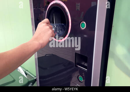 Käufer zurück, um ihre Flaschen und Dosen von wiederverwendbaren Verpackungen in einem umgekehrten Getränkeautomat Stockfoto