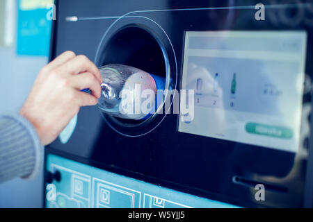 Käufer zurück, um ihre Flaschen und Dosen von wiederverwendbaren Verpackungen in einem umgekehrten Automaten. Stockfoto