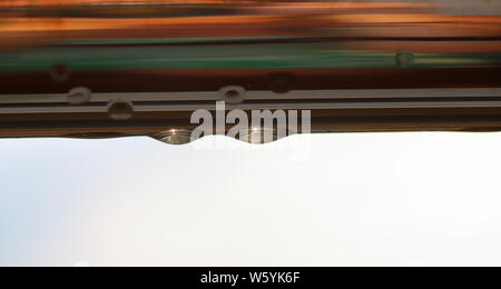 Regentropfen/Tropfen nach unten hängen auf Metall horizontalen Rohr, bunte Reflexionen, Kopieren, abstrakt. Stockfoto