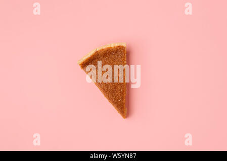 Traditionelle Pumpkin Pie Slice auf rosa Papier Hintergrund. Oben sehen Sie eine Torte teil. Minimale Bild der letzten Kreissegment. Thanksgiving Dessert Stockfoto