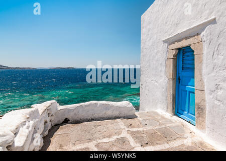 Mykonos, Griechenland. Traditionelles weißes Gebäude mit blauen Tür am Meer.. Stockfoto