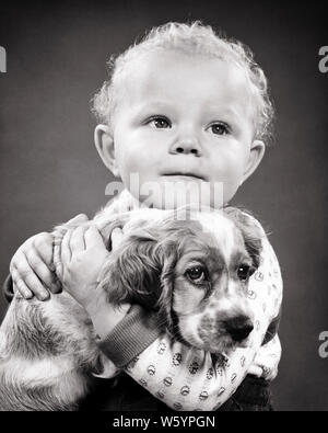 1950 kleine blonde Mädchen toddler Holding umarmt JUNGEN SAD-eyed Cocker Spaniel Welpen Hund suchen bei CAMERA-d 3834 HAR 001 HARS SPIRITUALITÄT VERTRAUEN COCKER B&W TRAURIGKEIT AUGENKONTAKT SÄUGETIERE KOPF UND SCHULTERN SCHUTZ STÄRKE FANGZÄHNE WAHL COCKER SPANIEL HÜNDCHEN VERBINDUNG KONZEPTIONELLER STILVOLLE BESTER FREUND CANINE JUGENDLICHE SÄUGETIER ZWEISAMKEIT BABY GIRL SCHWARZ UND WEISS KAUKASISCHEN ETHNIE HAR 001 ALTMODISCH Stockfoto