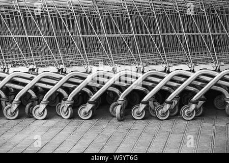 Shopping Carts geordnet in einer Reihe auf der Straße in der Nähe des Supermarktes. Close up Rad der Warenkorb. Konzept der Shopping. Selektive konzentrieren. Stockfoto