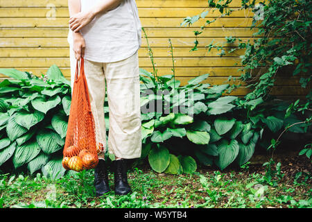 Eine Frau steht auf der Vorderseite der gelben wand mit Einkaufstaschen aus Baumwolle Stockfoto