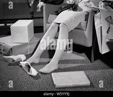 1960 FUSSKRANKEN ERSCHÖPFT FRAU SHOPPER VON TAILLE SITZEND ERSTRECKTE SICH IN STUHL SCHUHE AUF DEM BODEN INMITTEN EINKÄUFE UND PAKETE - s 14145 HAR 001 HARS B&W SHOPPER SHOPPER GLÜCK UND IN KONZEPTIONELLE BEAT PAKETE ENTSPANNUNG SHOP BIS ZUM UMFALLEN SPRAWLED TAILLE JUNGEN ERWACHSENEN FRAU inmitten von SCHWARZEN UND WEISSEN KAUKASISCHEN ETHNIE ERMÜDET HAR 001 ALTMODISCH KÄUFE MÜDE ABGENUTZT Stockfoto