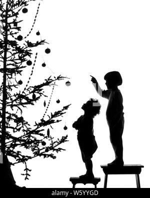 1920 s SILHOUETTE VON ZWEI KINDERN SUCHEN AUF geschmückten Weihnachtsbaum-s 1586 HAR 001 HARS GESCHWISTER EINGERICHTET SCHWESTERN B&W GLÜCK SILHOUETTED FRÖHLICHE GESCHWISTER DEZEMBER KONZEPT KONZEPTIONELL DEZEMBER 25 anonyme SYMBOLISCHE KONZEPTE WACHSTUM FRÖHLICHE JUGENDLICHE MITEINANDER BABY GIRL SCHWARZ UND WEISS HAR 001 ALTMODISCHE DARSTELLUNG Stockfoto