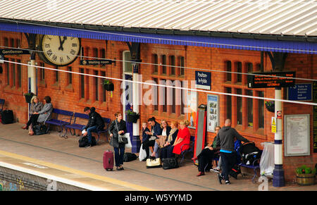 Die Menschen warten auf einen Zug auf der Plattform in der Poulton-Le-Fylde Bahnhof, Lancashire, Großbritannien Stockfoto
