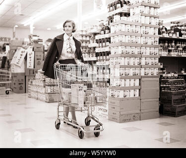 1960er Jahre 1970er Jahre FRAU MANTEL DRAPIERT AUF SCHULTERN DRÜCKEN WARENKORB IM SUPERMARKT SUPERMARKT-s 17817 HAR 001 HARS DAMEN PERSONEN GESCHÄFTE VERTRAUEN DRAPIERT B&W SHOPPER HAUSWIRTSCHAFTSLEITERIN SHOPPER HAUSFRAUEN ENTDECKUNG KART STOLZ KONSERVEN GELEGENHEIT BLUSE HAUSFRAUEN SPEICHERT KONZEPTIONELLE STILVOLLE COMMERCE Mitte - Mitte - ERWACHSENE FRAU SCHWARZ UND WEISS UNTERNEHMEN KAUKASISCHEN ETHNIE HAR 001 SAFT ALTMODISCH Stockfoto