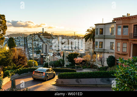 Die krummste Straße der Welt der Lombard Street in der Morgendämmerung. San Francisco ist erhellt von Morgen Sonne. Stockfoto