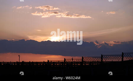 Zaun gegen die untergehende Sonne. beleuchtetes Foto Stockfoto