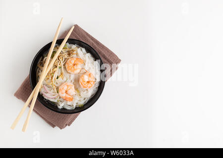 Traditionelle vietnamesische Nudelsuppe pho mit Garnelen in schwarz Schüssel auf weißem Hintergrund Stockfoto