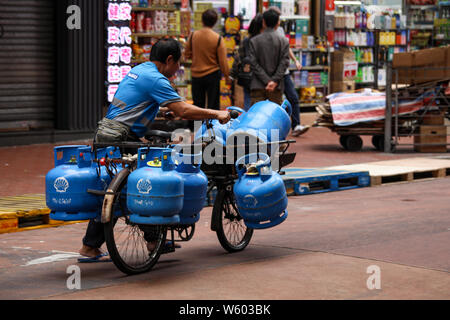 Mann mittleren Alters, der Gas mit dem Fahrrad in Mong Kok, Hongkong liefert Stockfoto