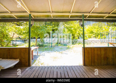 Die Aussicht vom Zimmer ohne Wände auf der Kinderschaukel. Bungalows ohne Wände sind in Ländern mit heißem Klima gebaut. Stockfoto