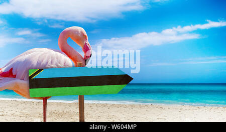 Sansibar Flagge auf hölzernen Tisch am Strand Hintergrund mit rosa Flamingo. Es liegt am Strand und klares Wasser von Meer und blauer Himmel im Hintergrund. Es ist Stockfoto