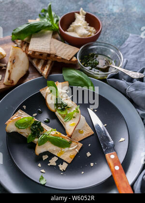 Kekse mit Frischkäse und Birne Schichten. Hot Sauce mit Knoblauch und Basilikum. Stockfoto