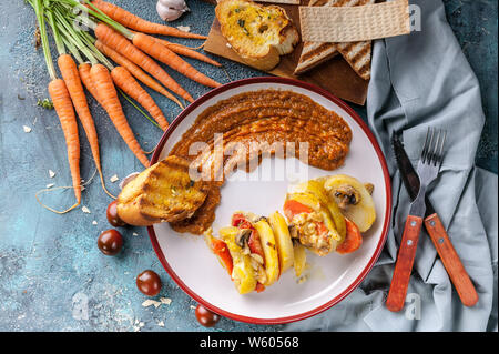 Vegetarisches Essen. Geschmorte Kartoffeln mit Zucchini, Karotten, Champignons und Käse. Karotten Püree mit Champignons. Ansicht von oben Stockfoto