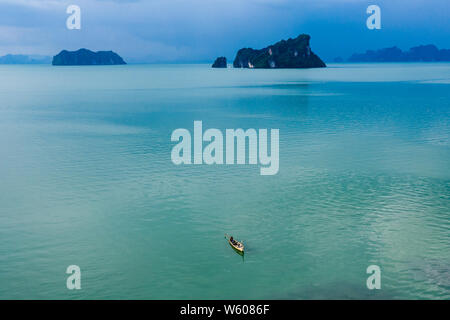 Luftaufnahme von einem kleinen traditionellen Fischerboot auf einer flachen, ruhigen tropischen Ozean in Thailand Stockfoto