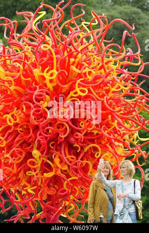 Zwei Frauen, die selfies vor einer spektakulären Glasskulpturen von Dale Chihuly in Kew Botanical Gardens West London England Großbritannien Stockfoto