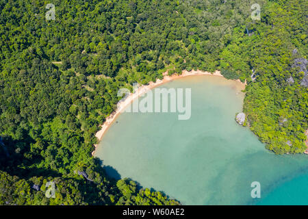 Antenne drone Blick auf einen schönen, abgelegenen tropischen Sandstrand von dichten, gebirgige Dschungel umgeben Stockfoto